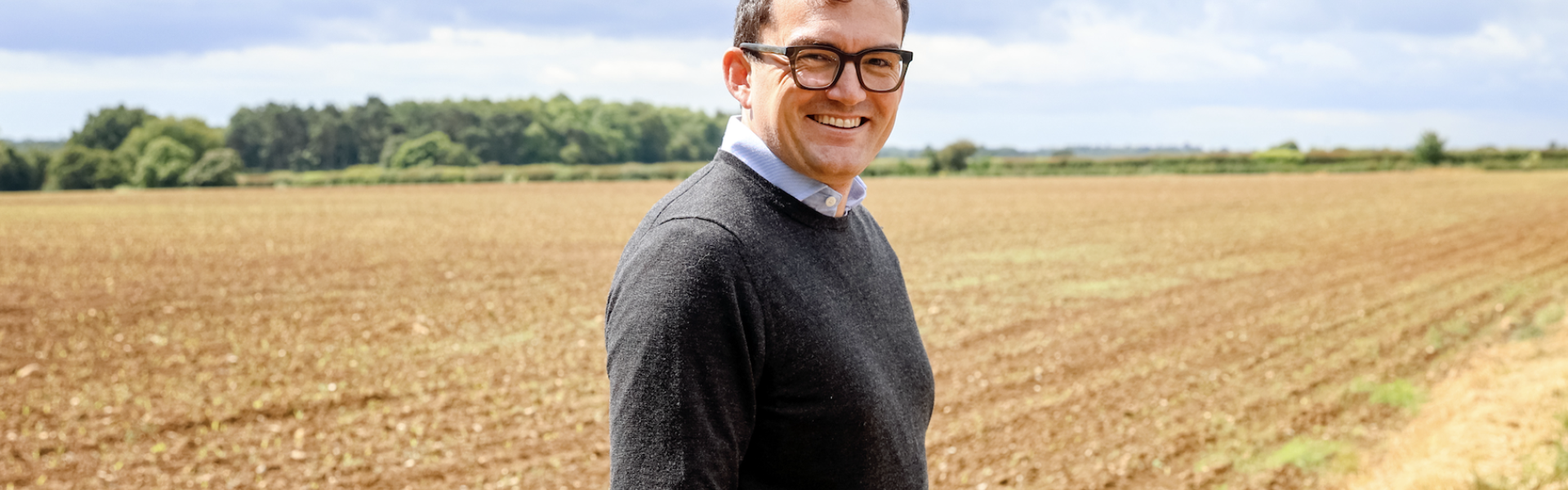 Patrick Spencer MP standing in a harvested field